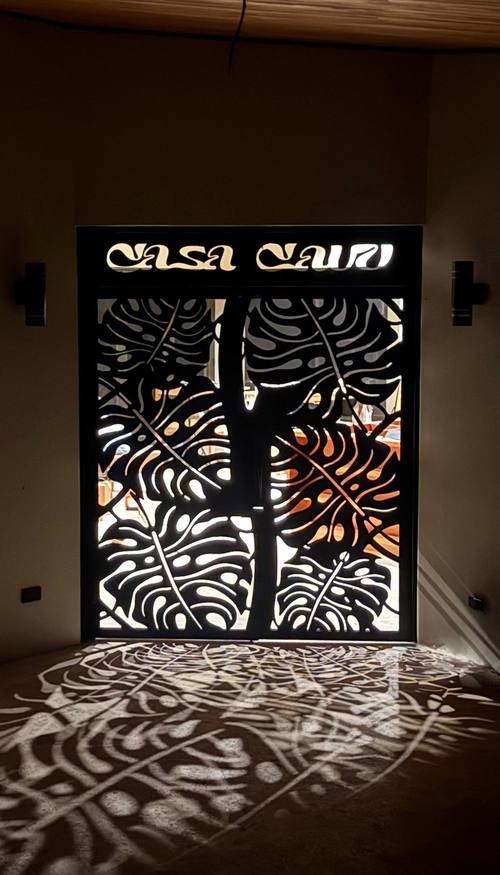 Illuminated Casa Cavu monstera gate at night